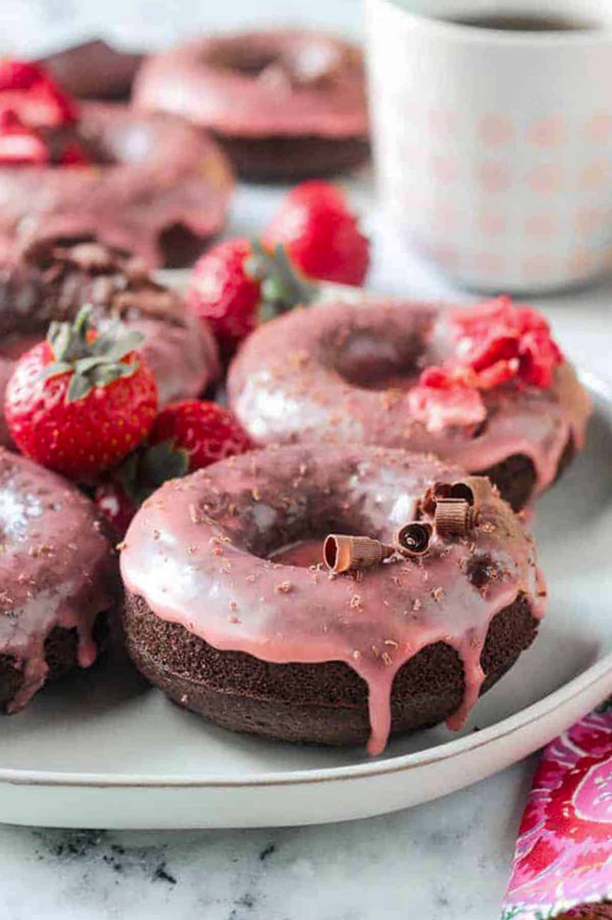 Close up of drippy strawberry glaze on a chocolate donut.