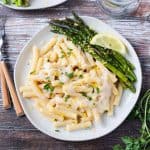 Overhead view of pasta in a vegan white sauce with a side of roasted asparagus.