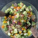 Chopped raw veggies mixed with vinaigrette in a glass bowl.