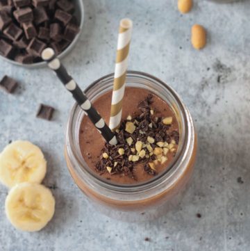 Overhead view of a Peanut Butter Chocolate Smoothie topped with chocolate chips and crushed peanuts.