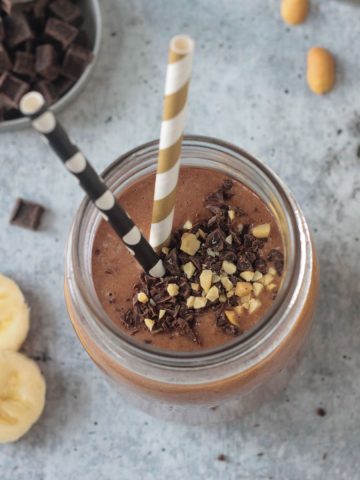Overhead view of a Peanut Butter Chocolate Smoothie topped with chocolate chips and crushed peanuts.