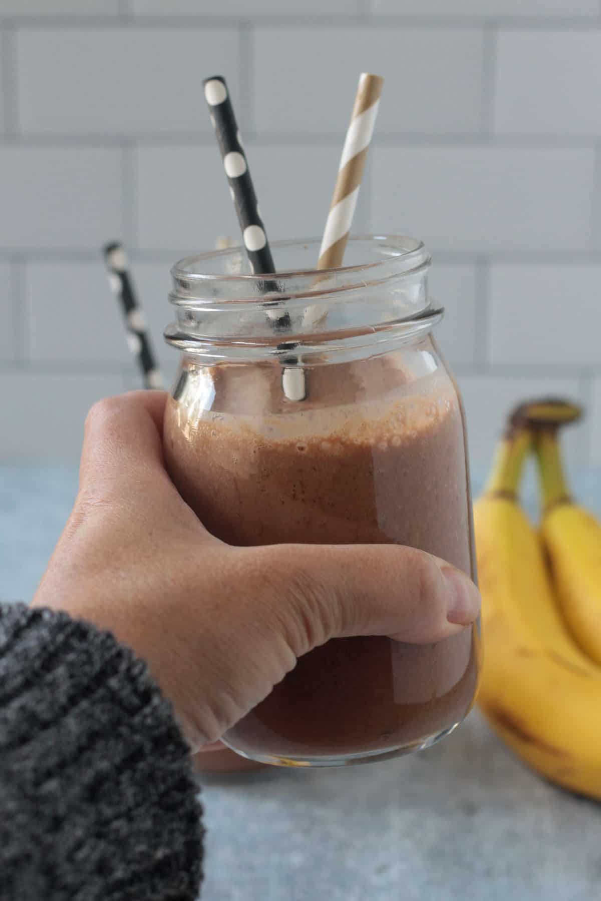 Adult hand holding up a chocolate smoothie.