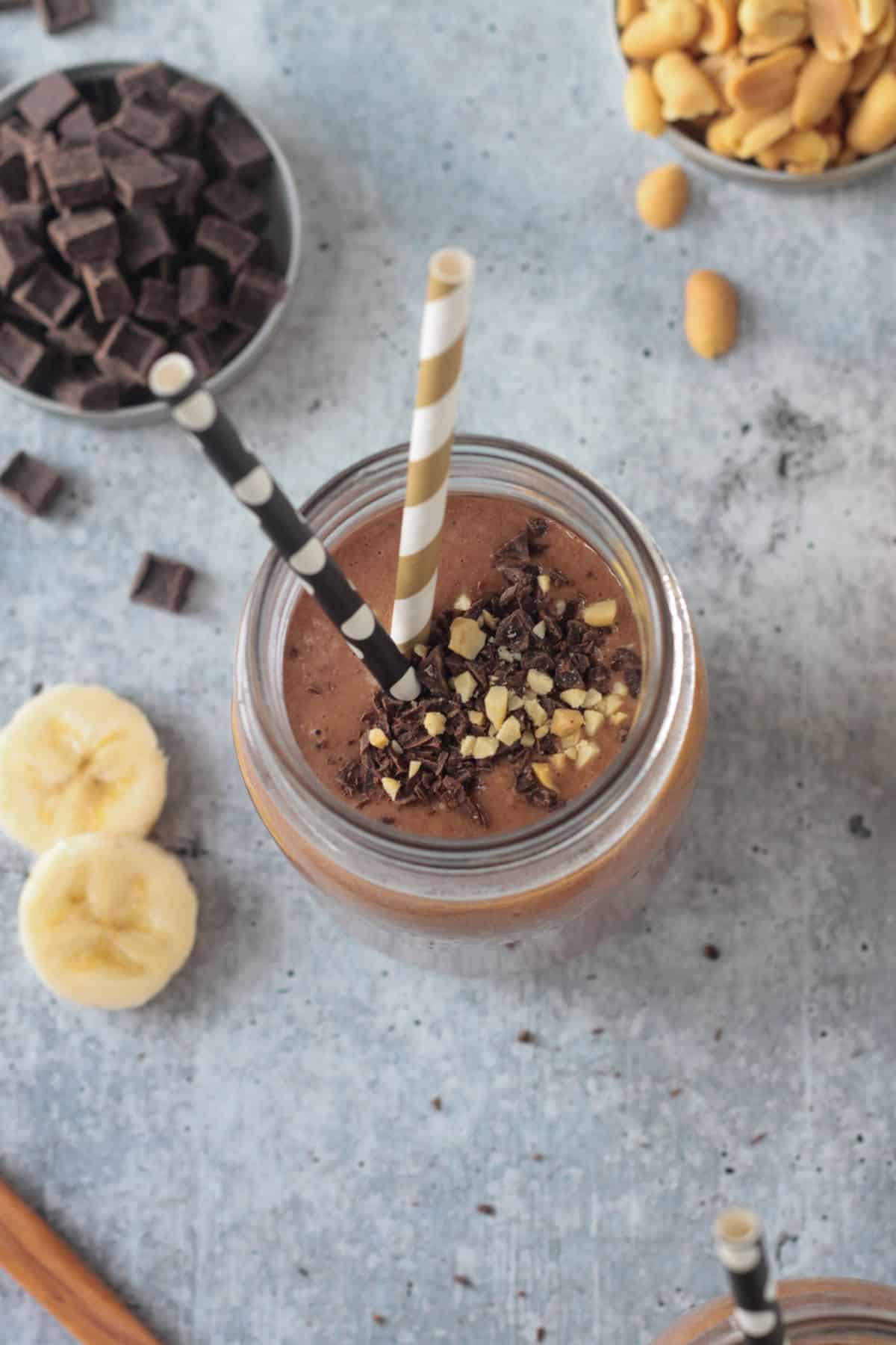 Overhead view of a peanut butter chocolate smoothie topped with chocolate chips and crushed peanuts.