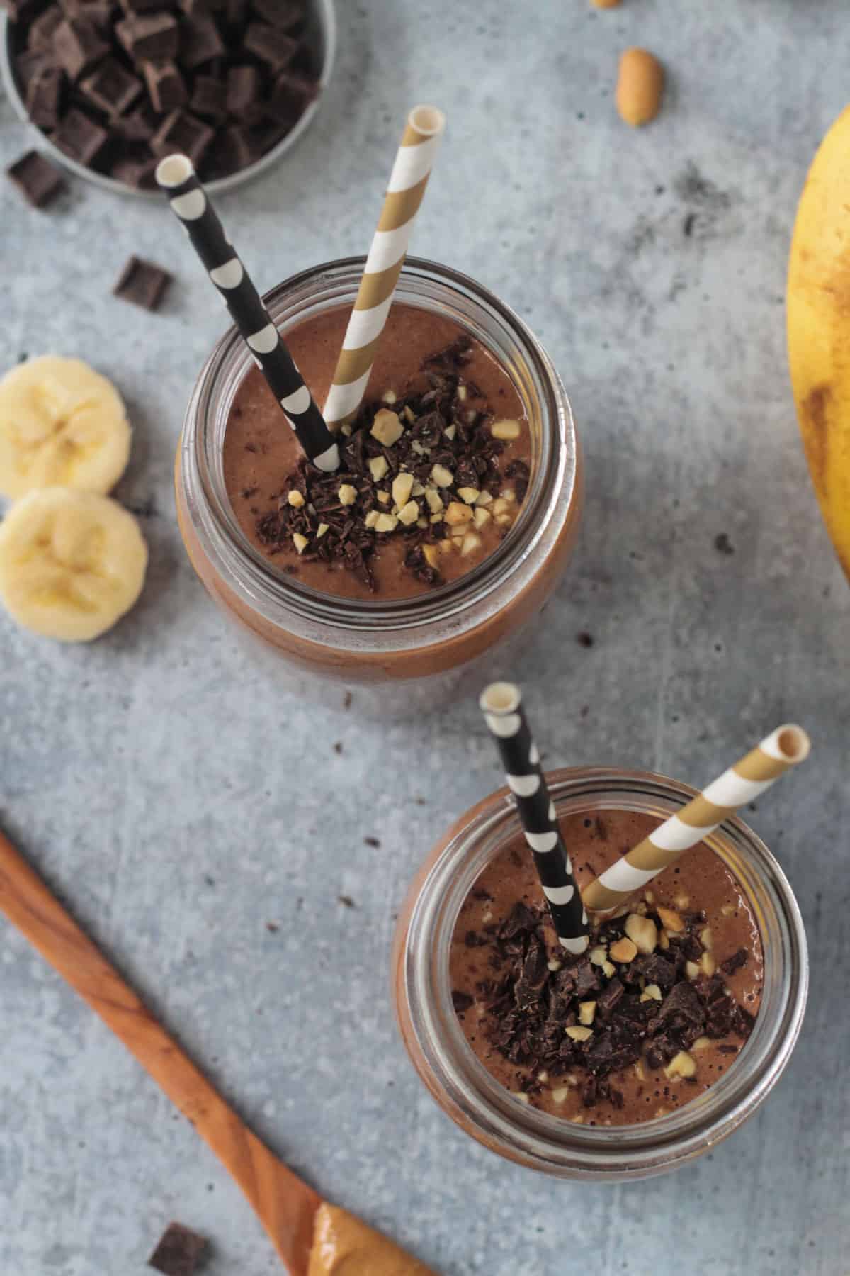 Two chocolaty drinks topped with chocolate chips and crushed peanuts.