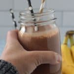 Adult hand holding up a chocolate smoothie.