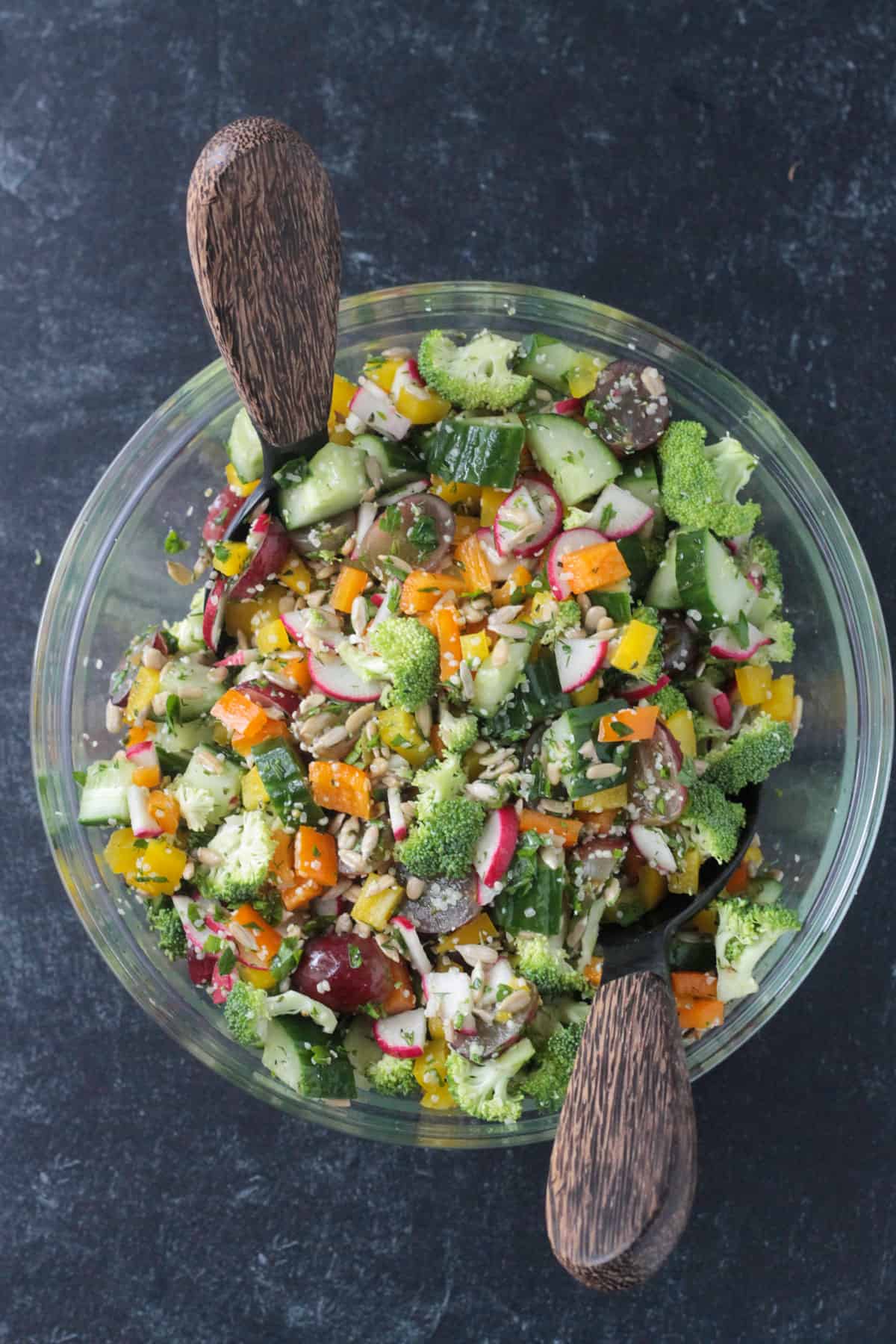 Chopped raw veggies mixed with vinaigrette in a glass bowl.