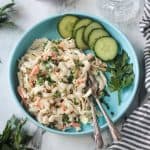 Vegan Macaroni Salad on a blue plate with two forks and a side of sliced cucumbers.