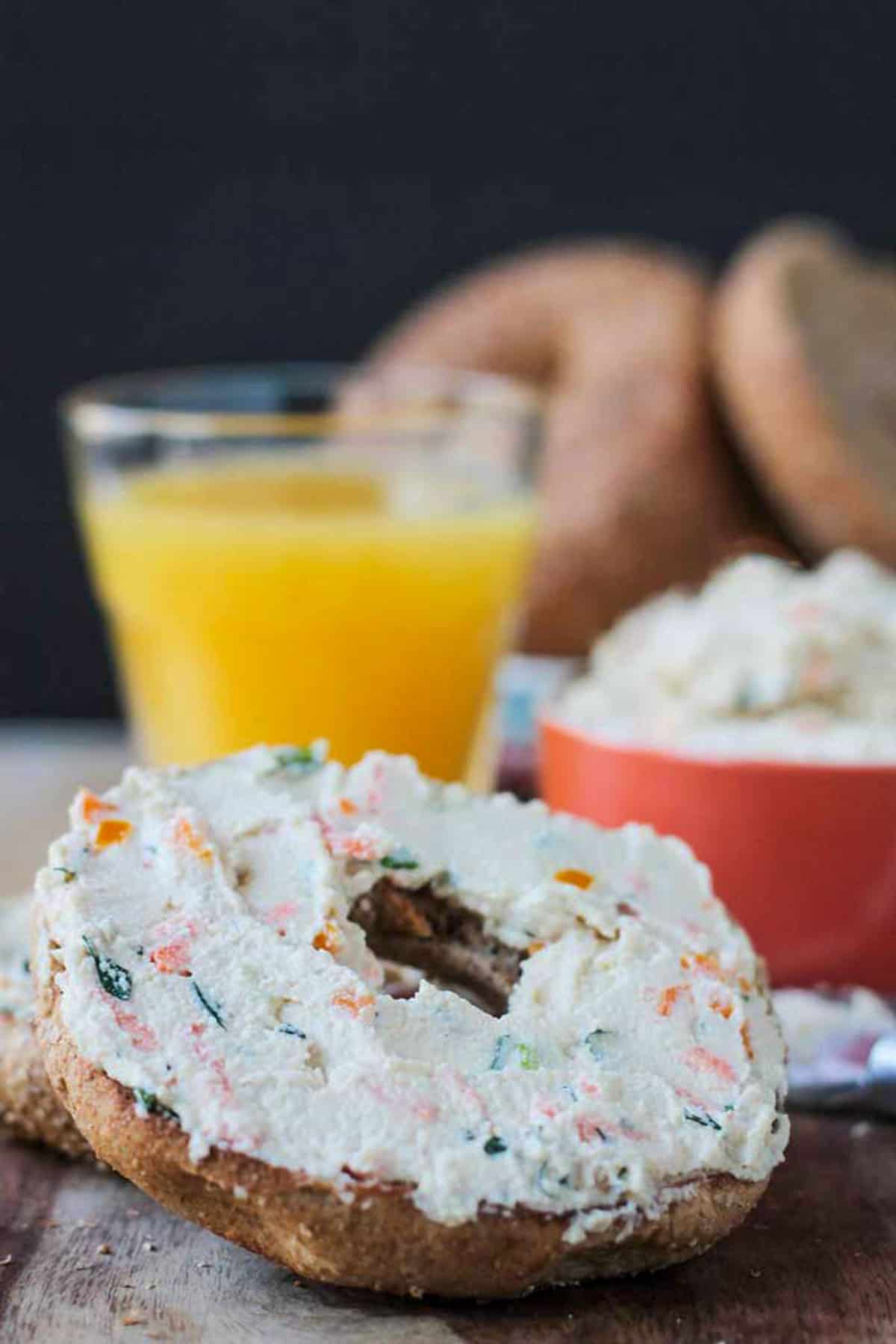 Close up for finely diced veggies in cream cheese on a bagel.