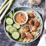 Oven baked tofu finished dish with rice, cucumbers, and sauce.