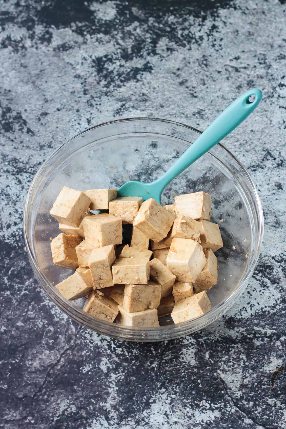 tofu cubes marinating in a glass bowl