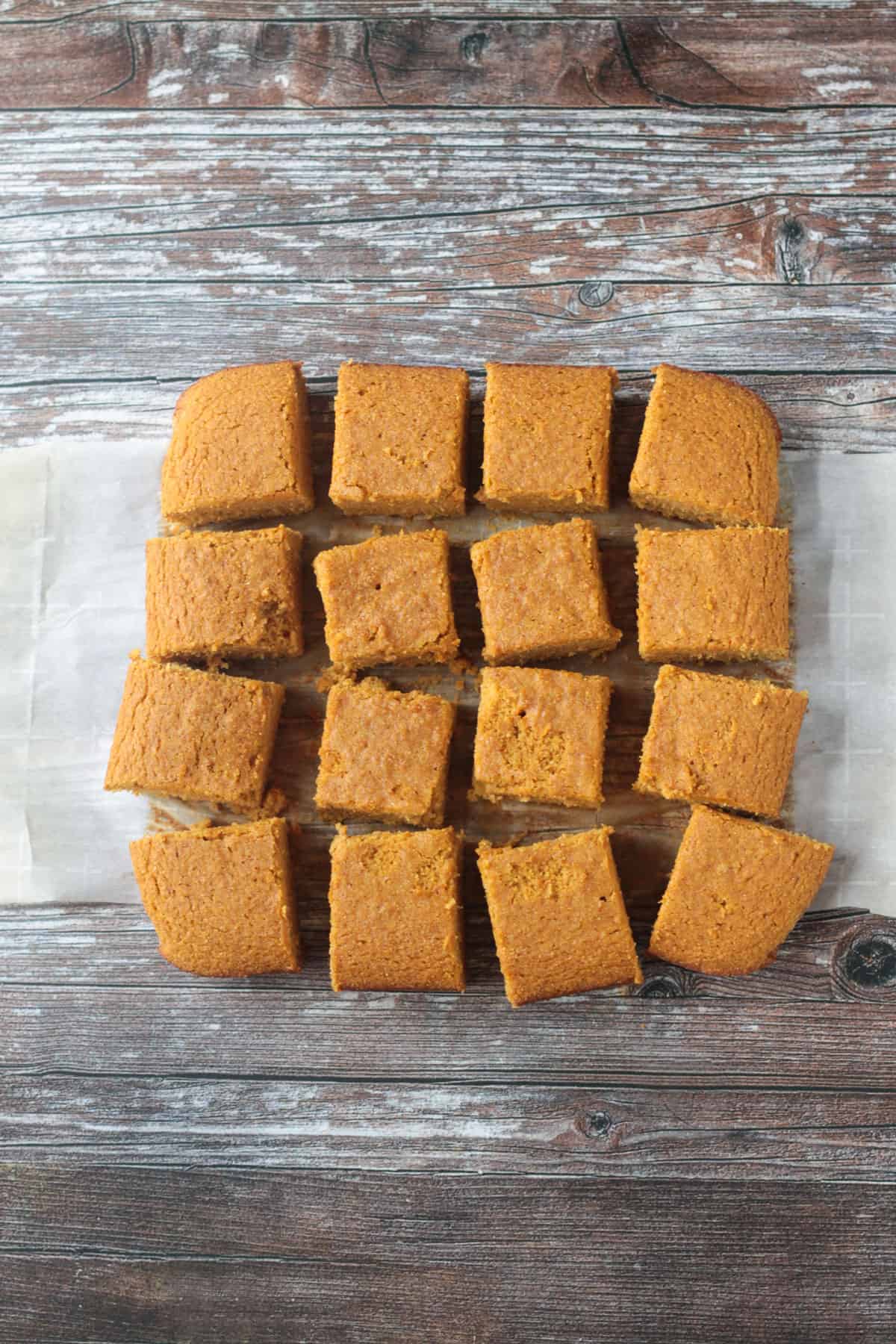 Squares of cornbread on a piece of parchment paper.
