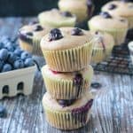 Stack of 3 vegan banana blueberry muffins in paper wrappers.