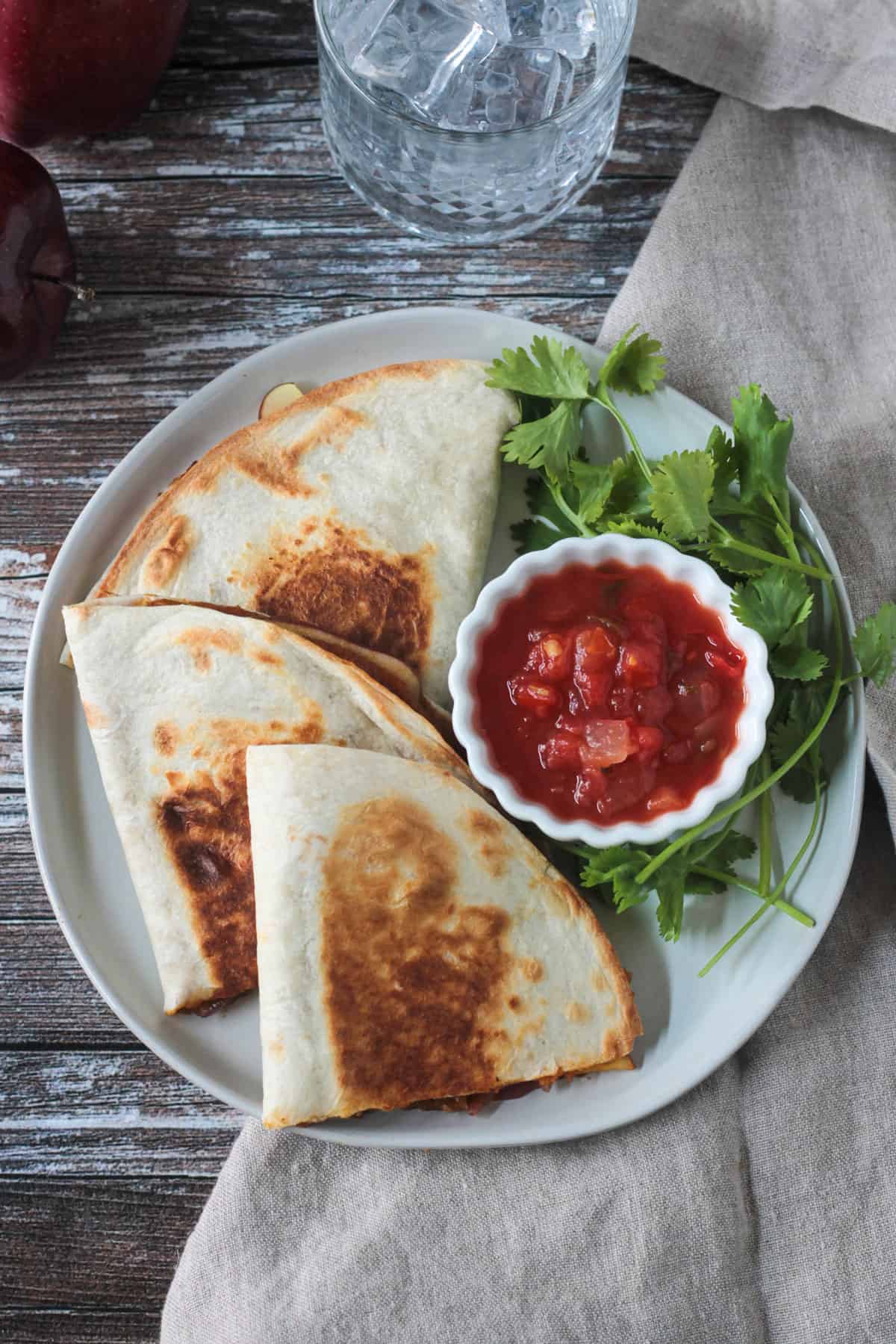 Overhead view of three halved vegan quesadillas next to a small bowl of salsa.