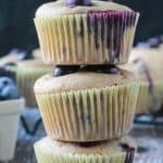 Close up of a stack of 3 blueberry muffins in paper liners.
