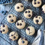 Batch of blueberry muffins on a black wire cooling rack.