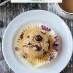 Overhead view of one vegan blueberry muffin in a paper liner.