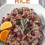 Thanksgiving rice with cranberries, citrus, and rosemary on a cream colored plate.