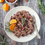 Thanksgiving rice with cranberries, citrus, and rosemary on a cream colored plate.