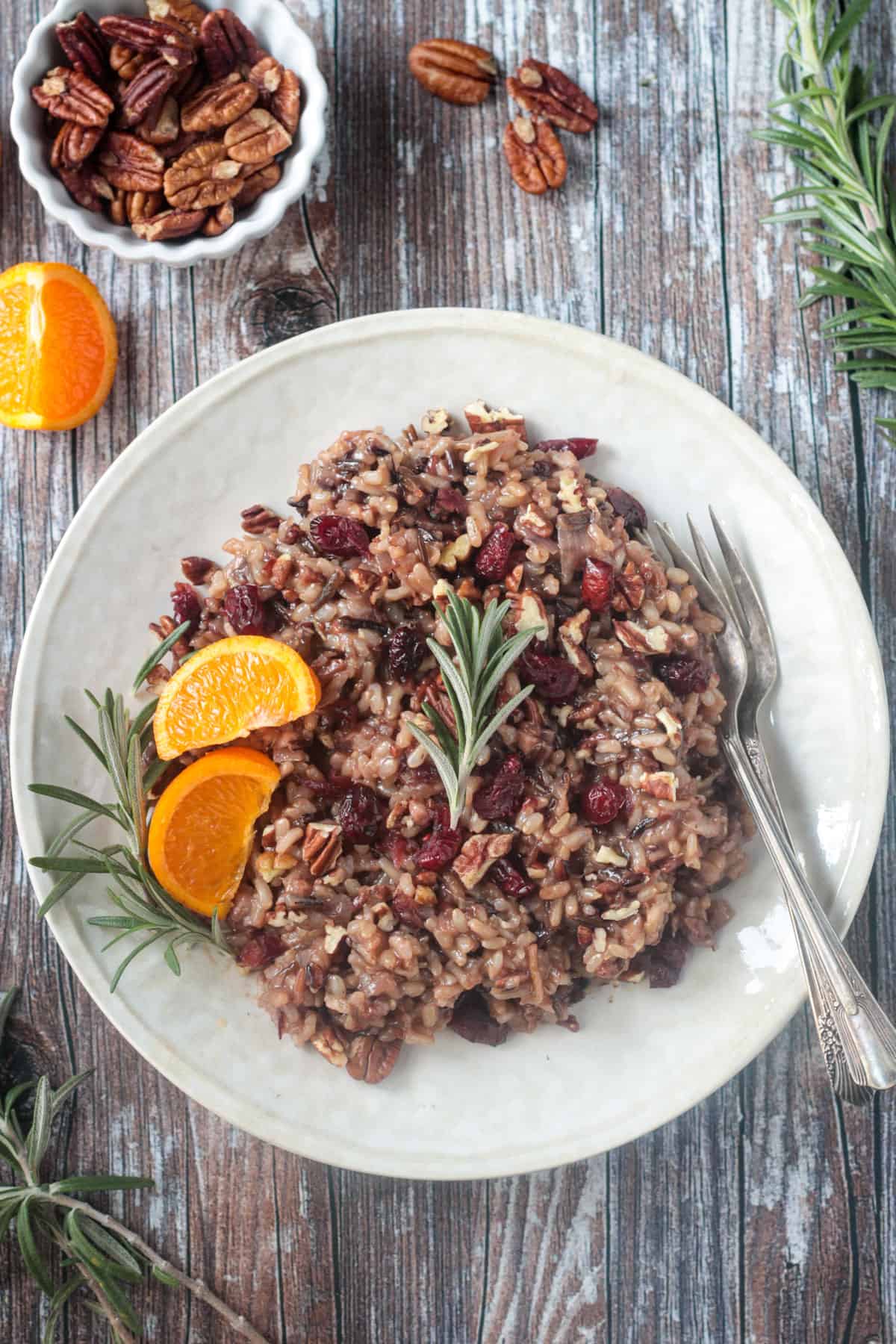 Thanksgiving rice with cranberries, citrus, and rosemary on a cream colored plate.