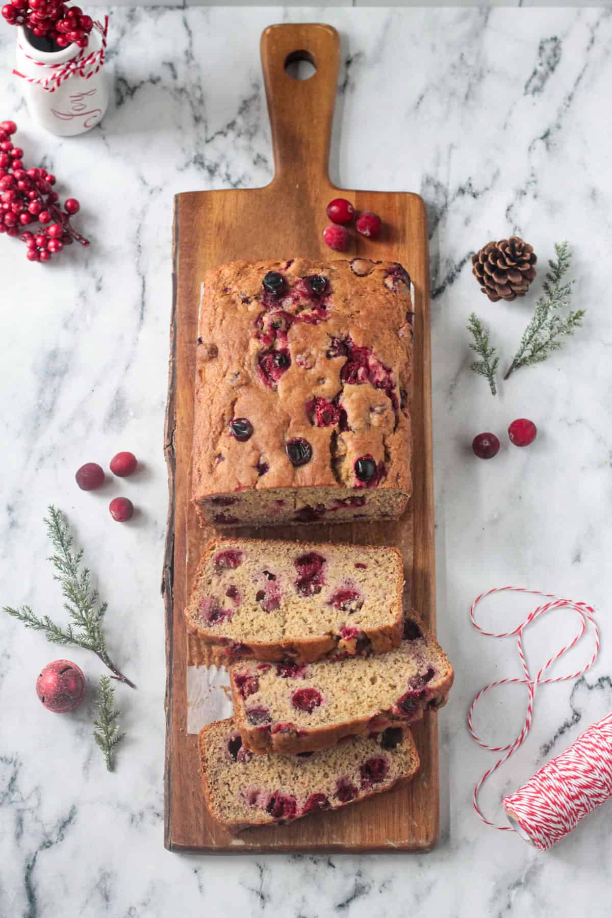 Loaf of cranberry banana bread on a wooden serving board