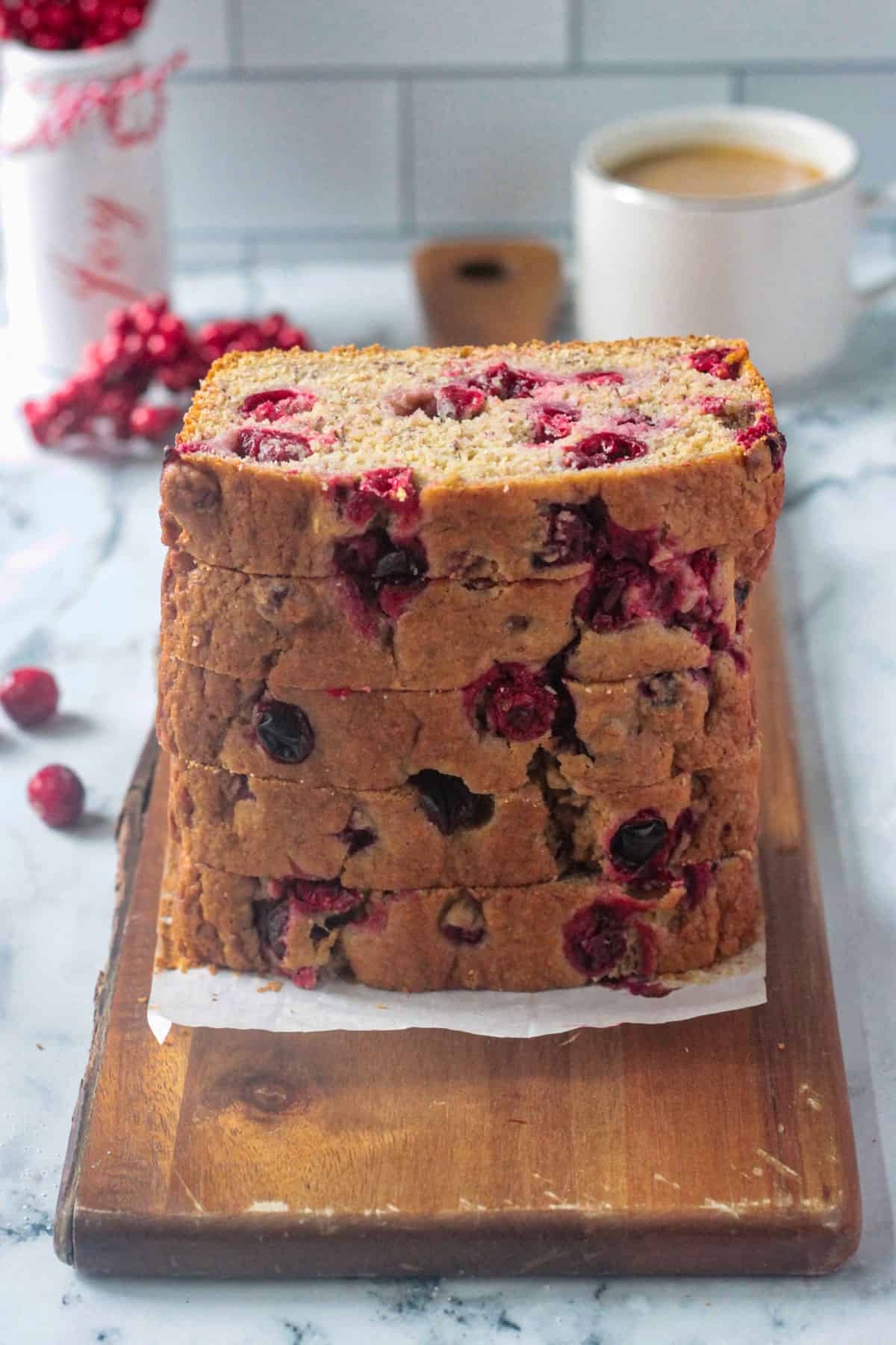 Slices of cranberry quick bread stacked high on a plate.