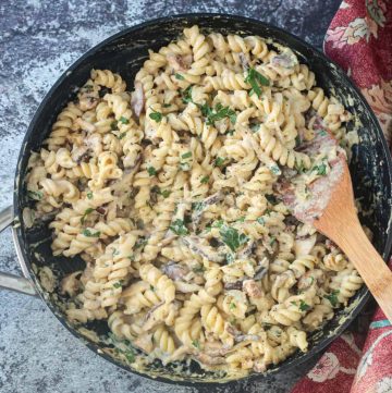 Rotini noodles in creamy mushroom sauce in a skillet.