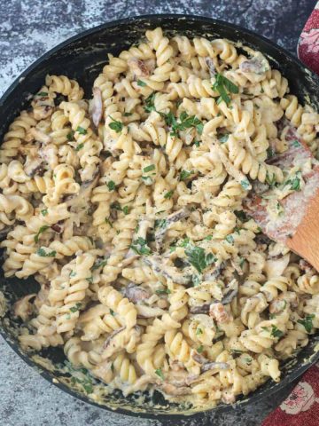 Rotini noodles in creamy mushroom sauce in a skillet.