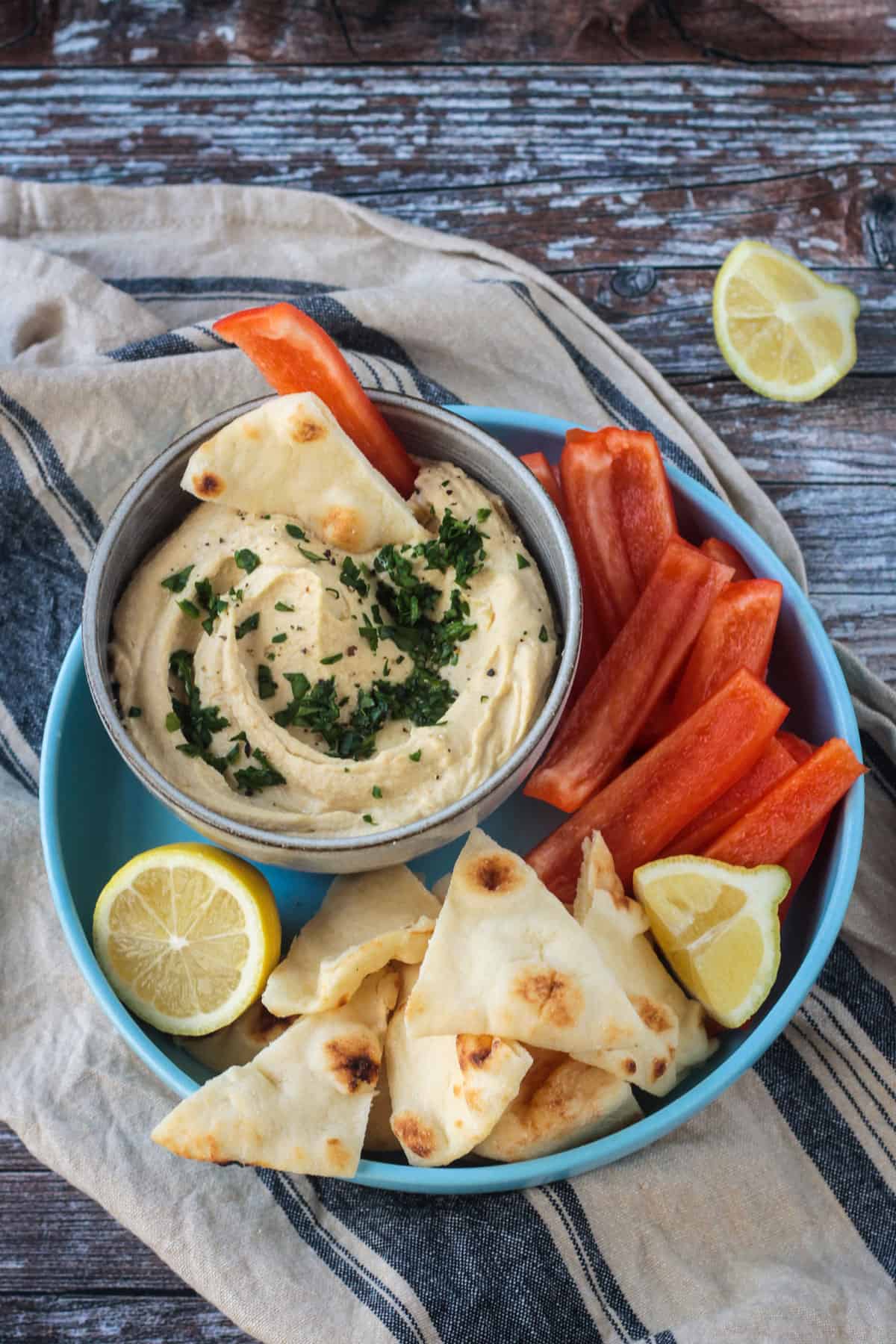 Bowl of oil free hummus next to pita triangles and red bell pepper strips.