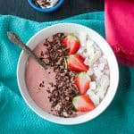 Strawberry smoothie bowl topped with sliced strawberries, coconut flakes, and chocolate shavings.