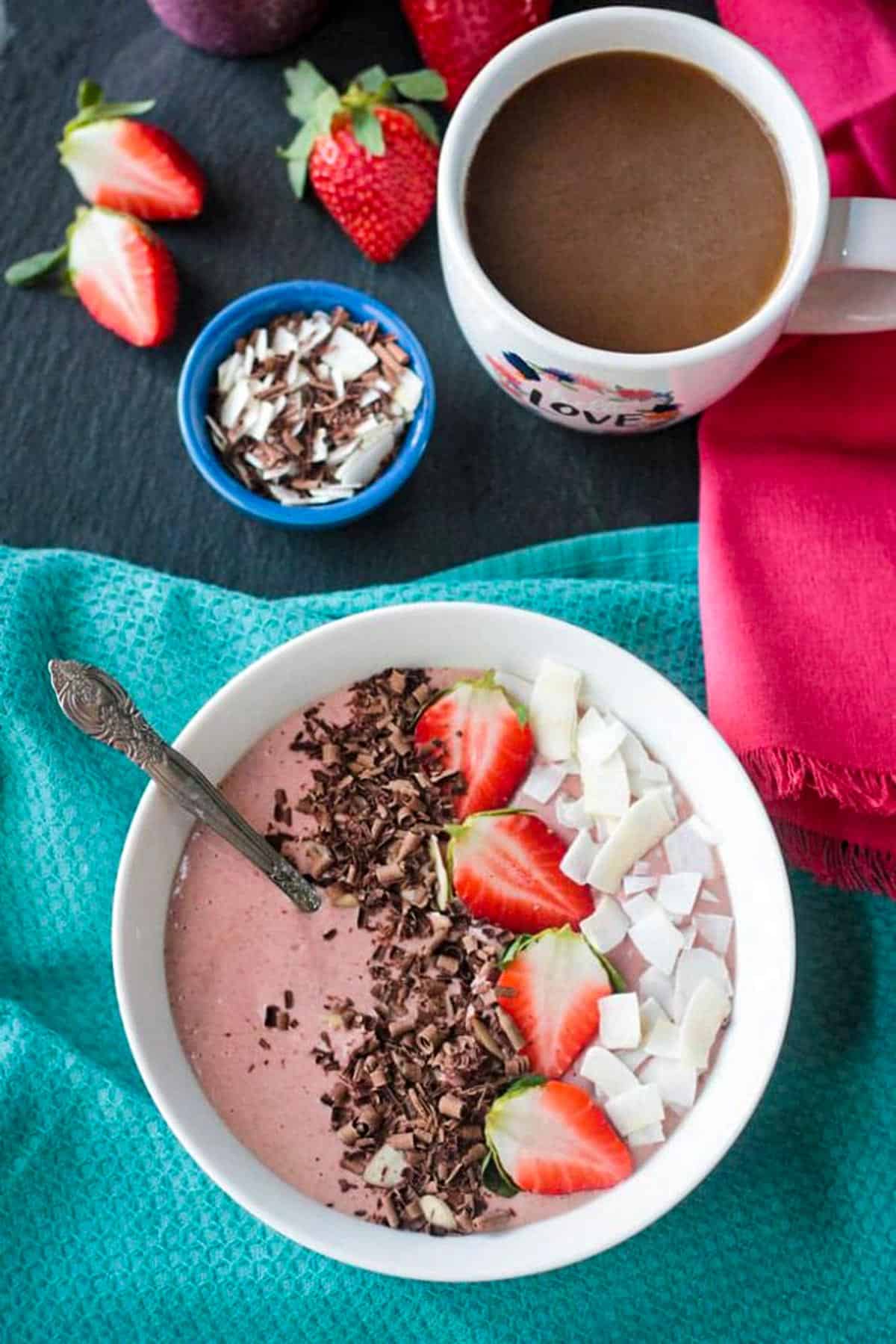 Strawberry smoothie bowl topped with sliced strawberries, coconut flakes, and chocolate shavings.