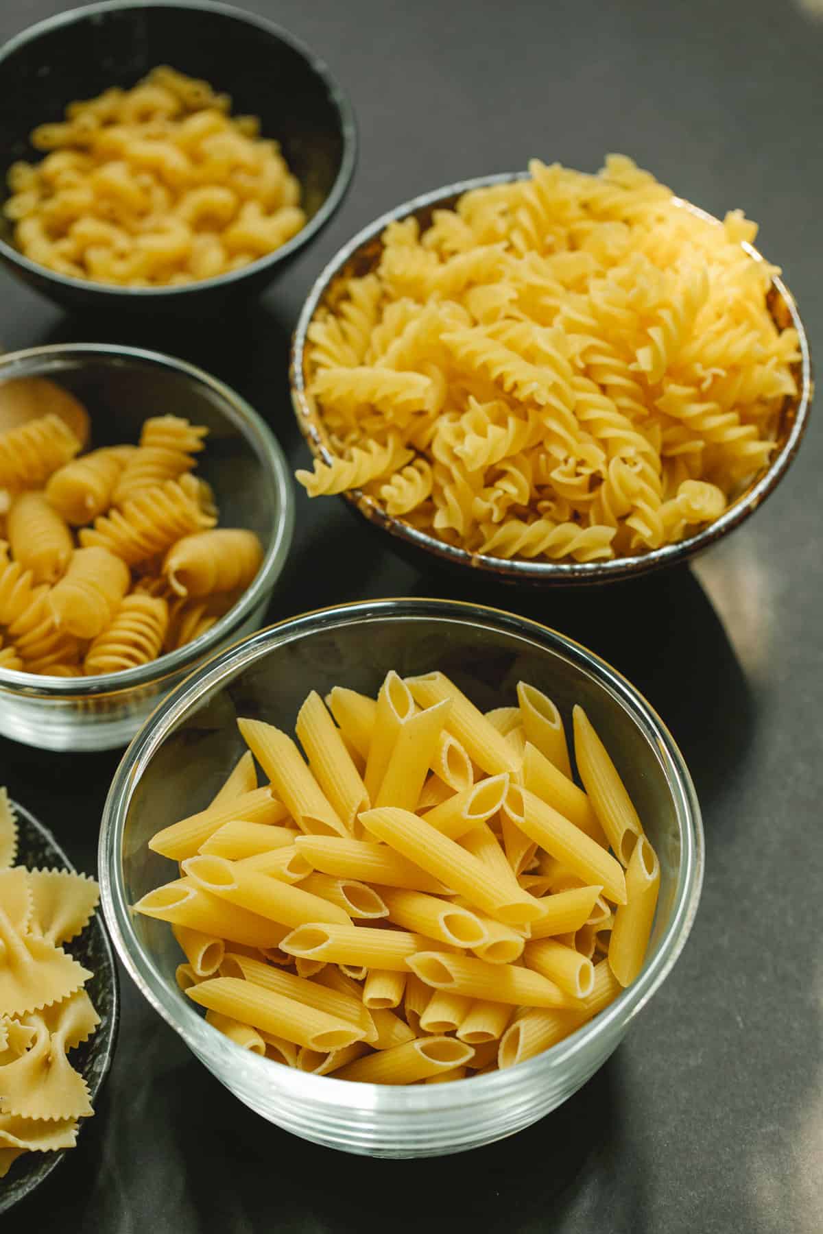 4 varieties of pasta shapes in individual bowls.