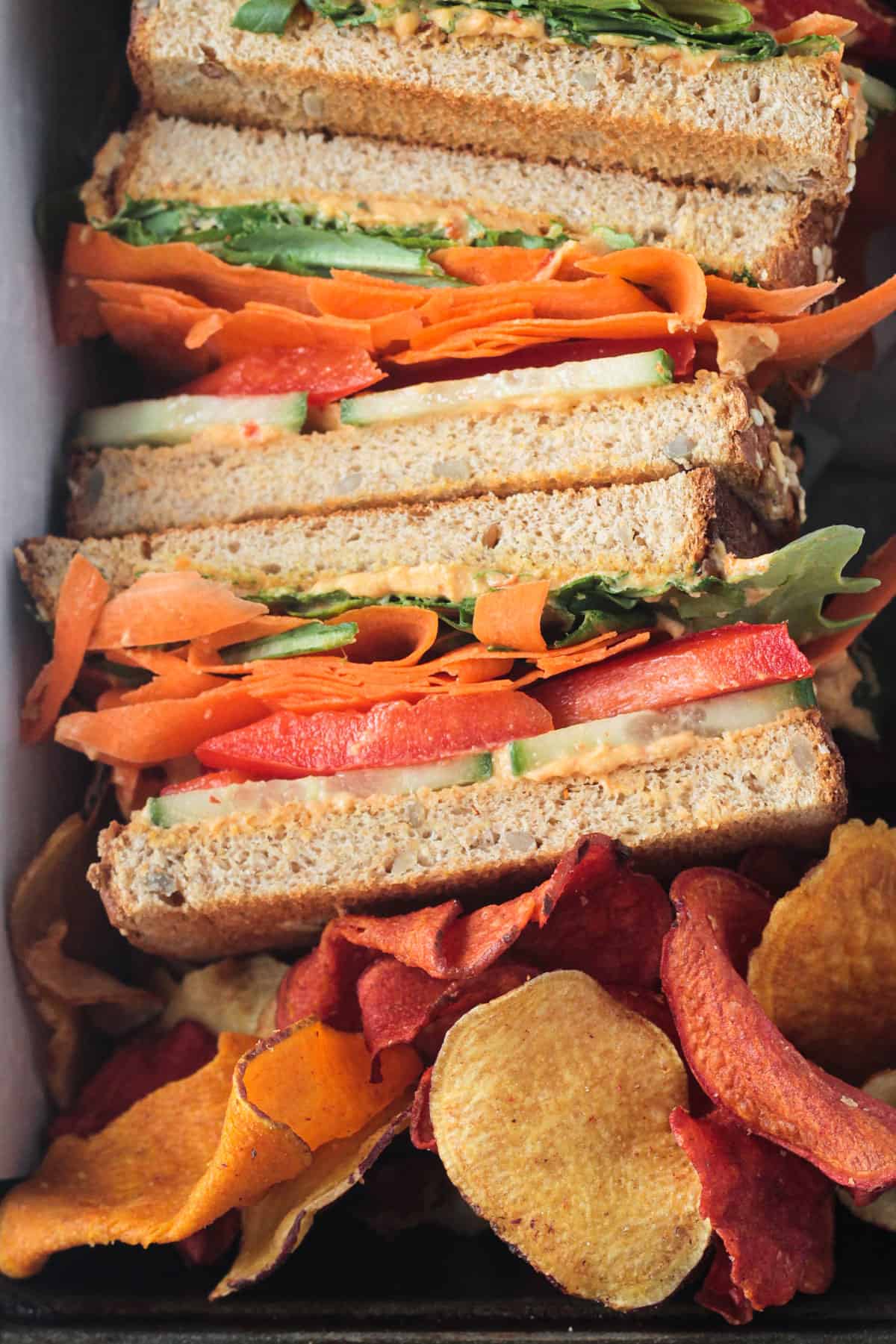 Close up of vegetables and hummus on a half of sandwich.