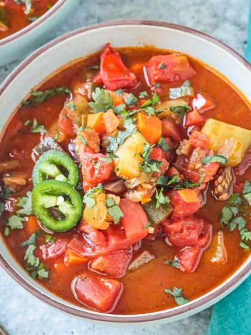 Bowl of veggie chili soup topped with jalapeño slices.