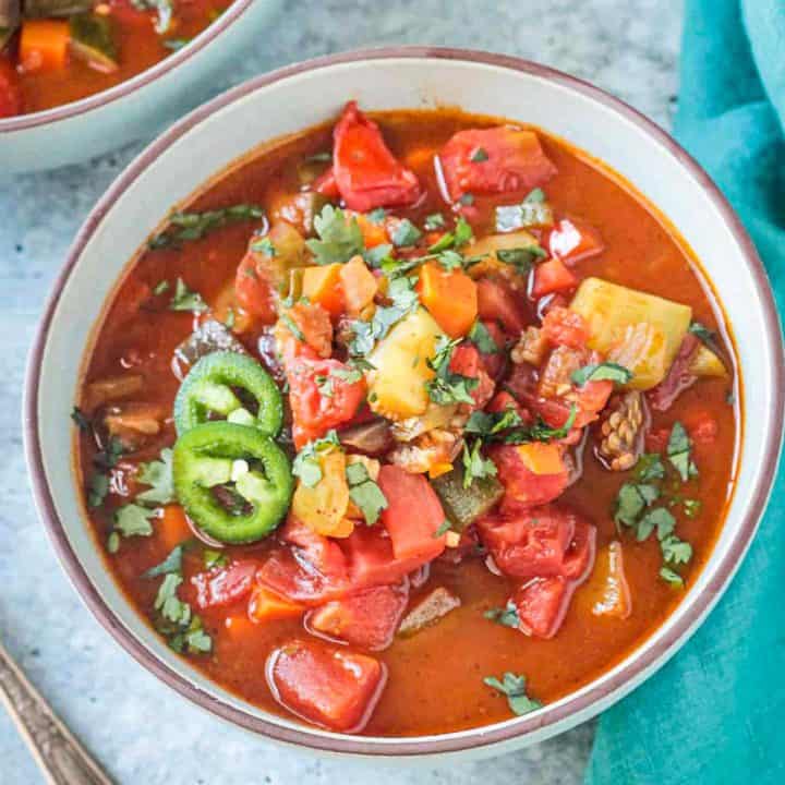 Bowl of veggie chili soup topped with jalapeño slices.