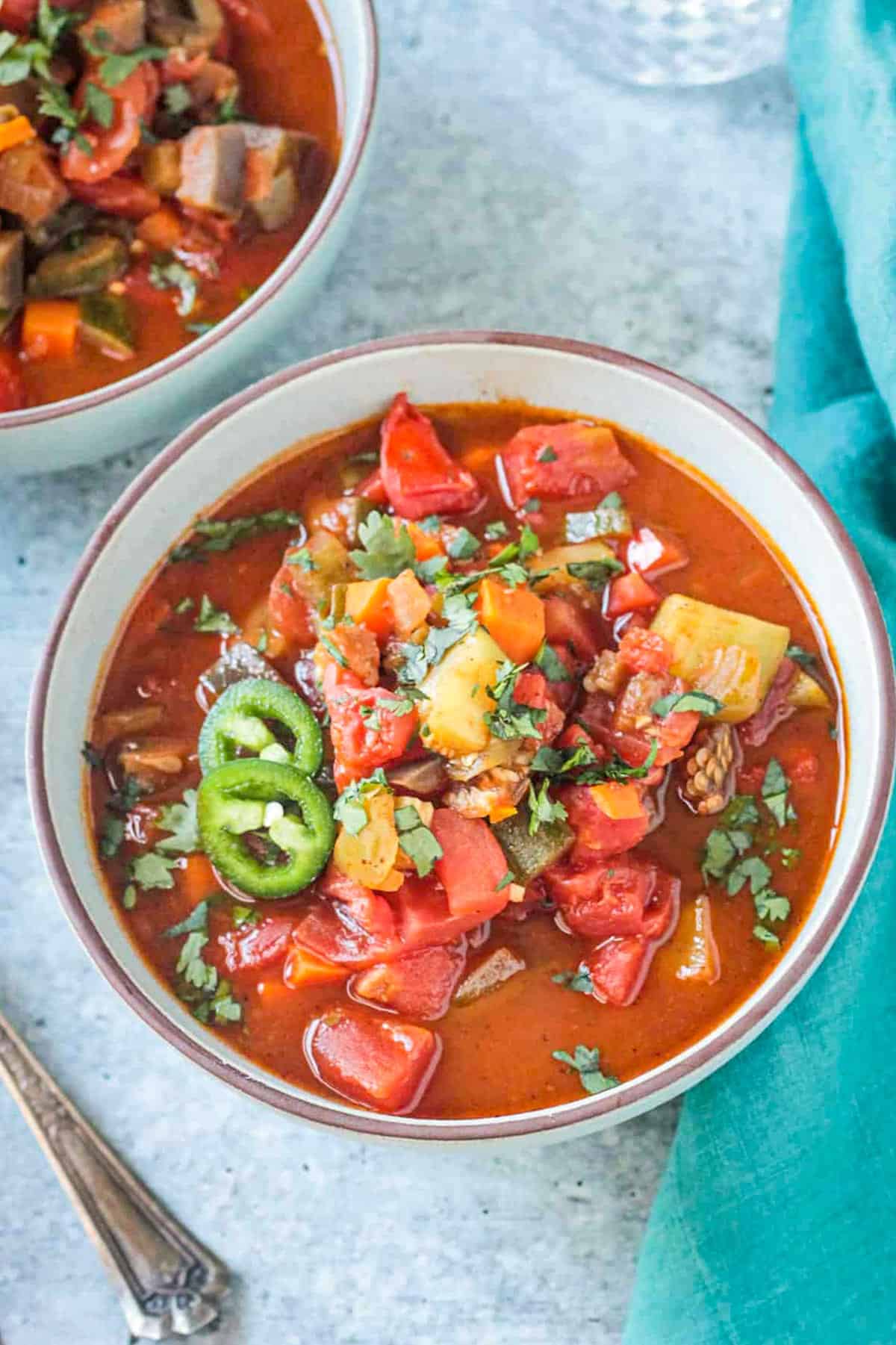 Bowl of veggie chili soup topped with jalapeño slices.