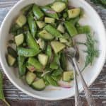 Two forks in a bowl of sugar snap pea salad.