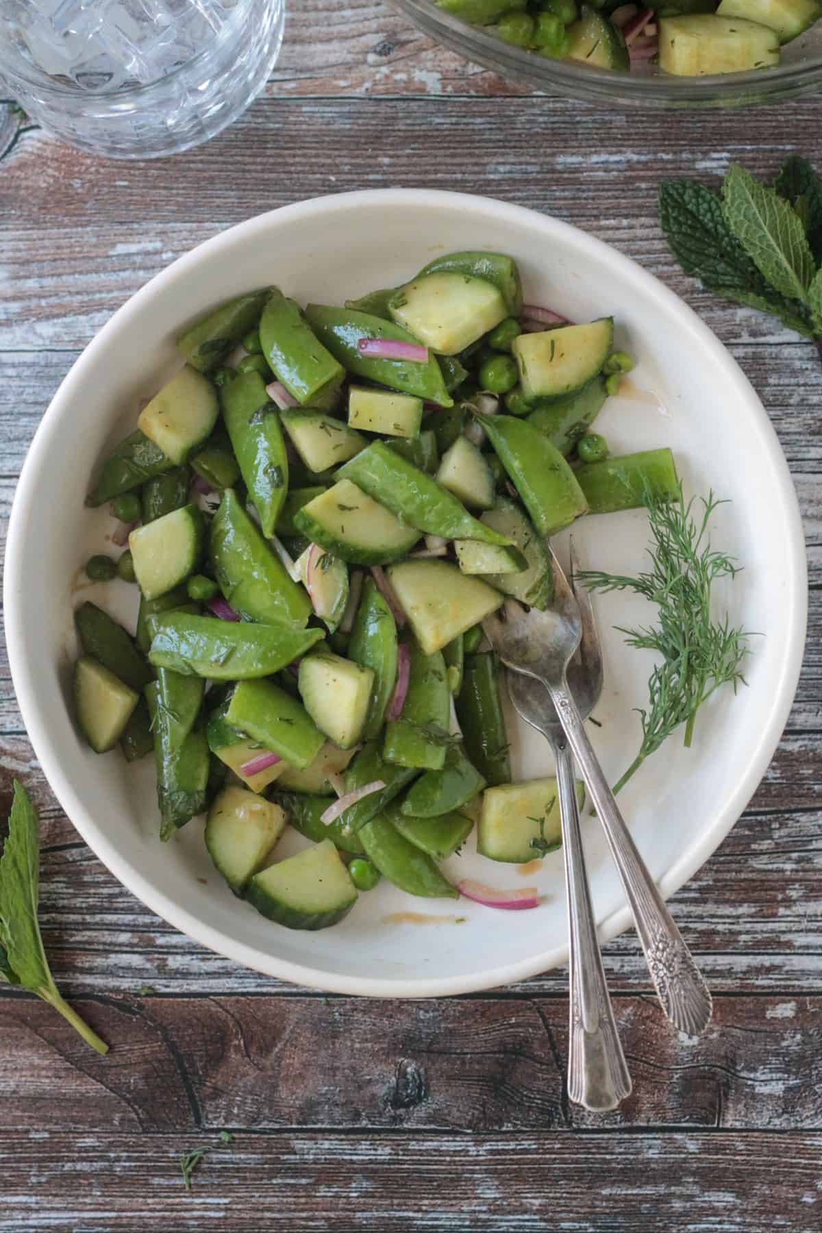 Two forks in a bowl of sugar snap pea salad.