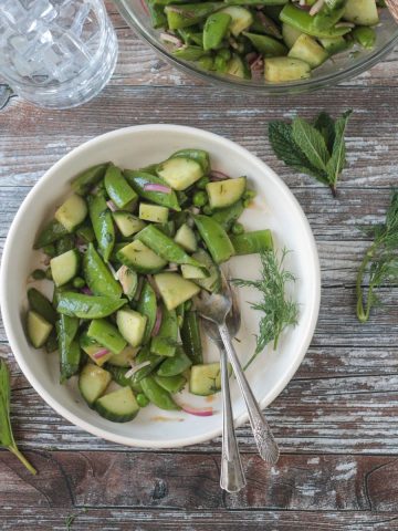 Two forks in a bowl of sugar snap pea salad.