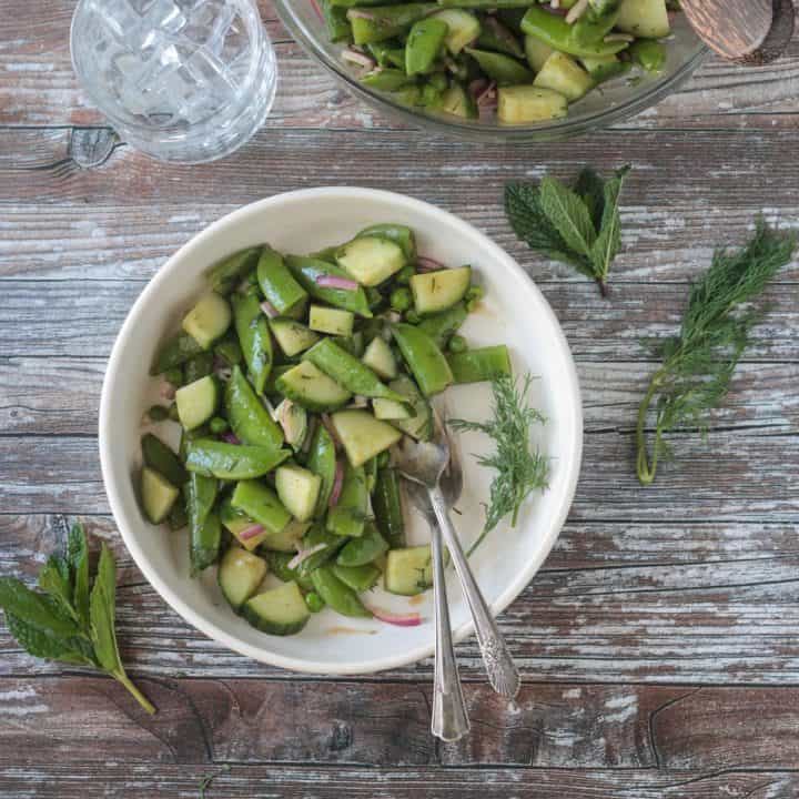 Two forks in a bowl of sugar snap pea salad.