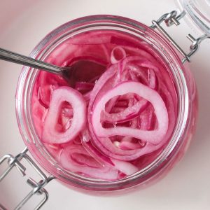 Fork in a an open jar of pickled red onions.