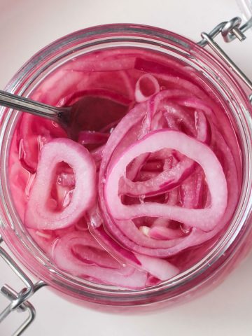 Fork in a an open jar of pickled red onions.