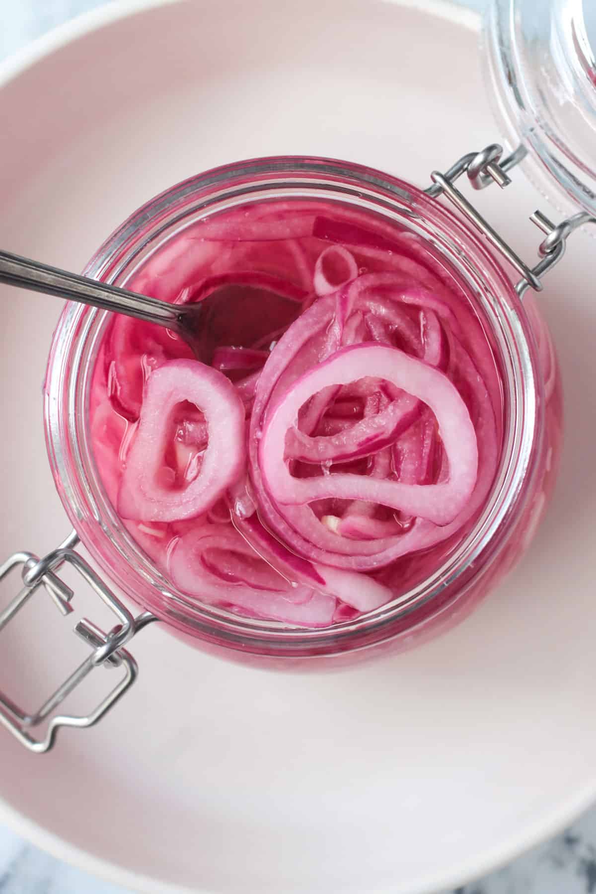 Fork in a an open jar of pickled red onions.