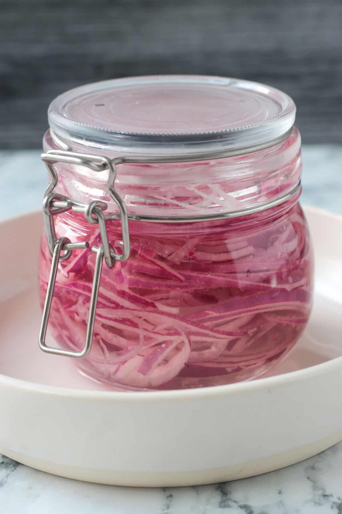 Pickled red onions in a jar with a closed lid.