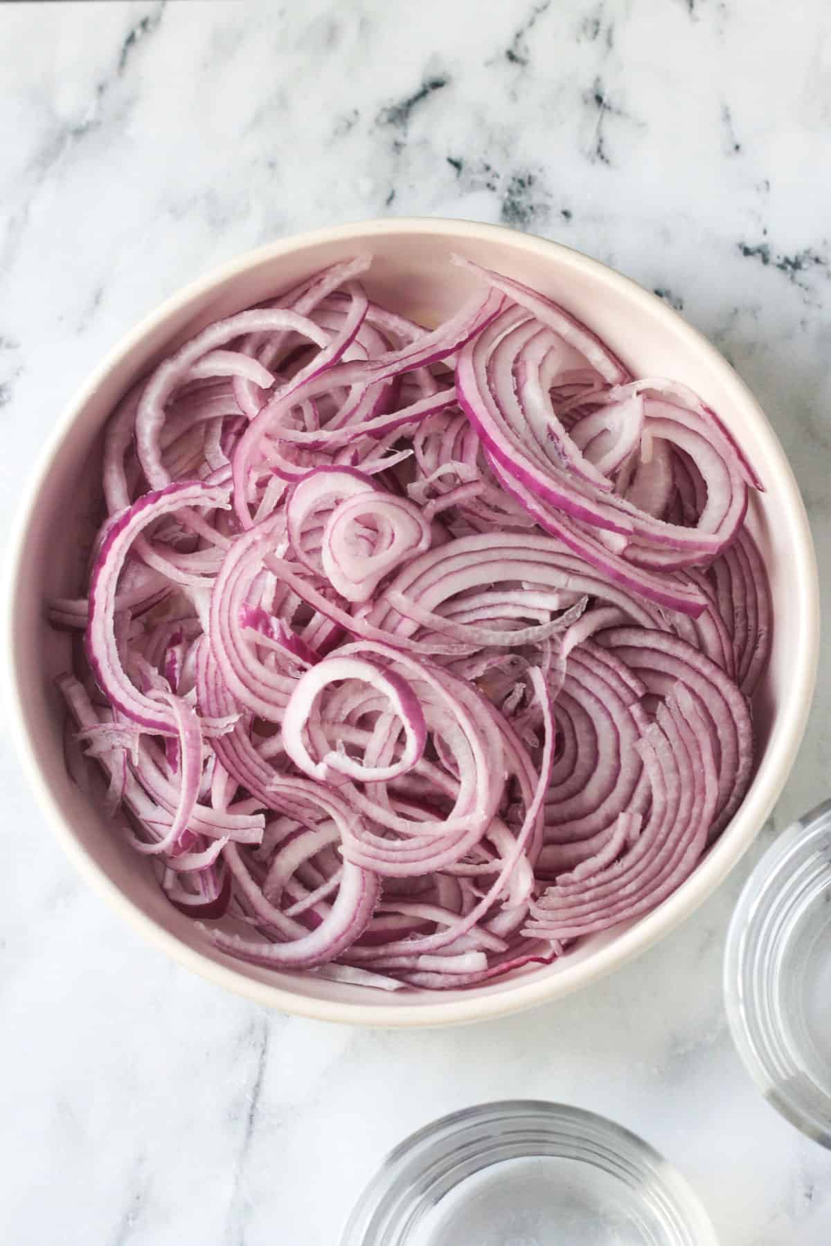 Bowl full of thinly sliced red onions.