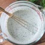 Hemp seed dressing in a glass bowl with a whisk.