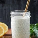 Creamy white hemp seed dressing in a jar with a gold whisk.