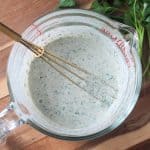 Hemp seed dressing in a glass bowl with a whisk.