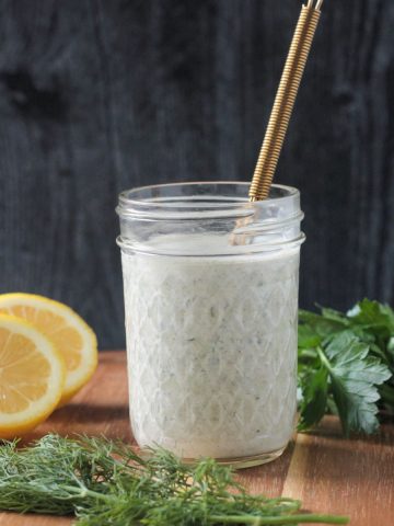 Creamy white hemp seed dressing in a jar with a gold whisk.