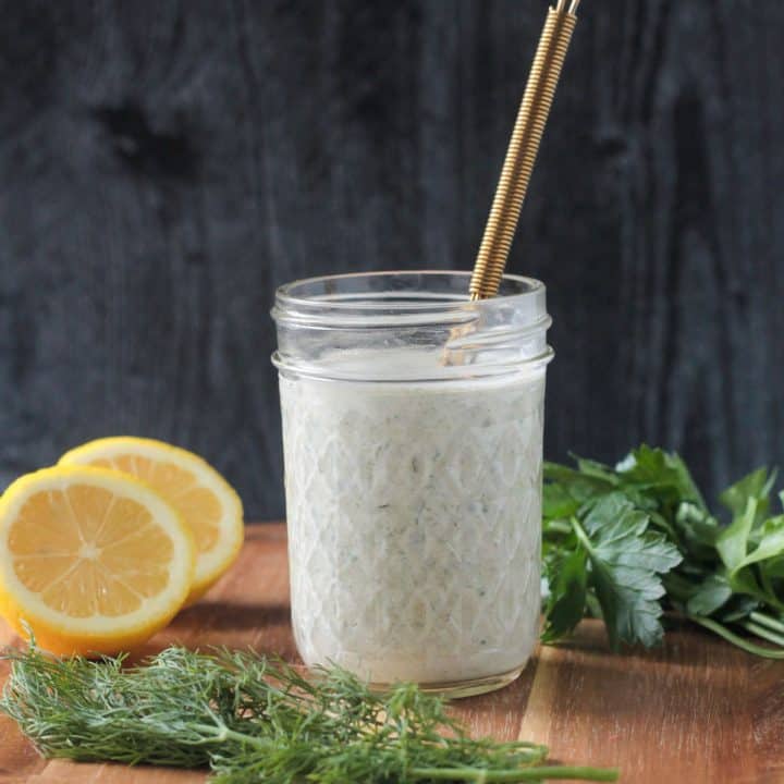 Creamy white hemp seed dressing in a jar with a gold whisk.