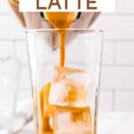 Pumpkin spice iced latte being poured from a blender over ice in a glass.